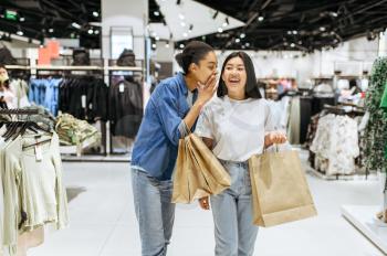 Happy girlfriends with purchases in bags, clothing store. Women shopping in fashion boutique, shopaholics, shoppers with purchase
