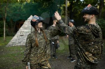 Team in camouflage and masks playing paintball, war on playground in the forest. Extreme sport with pneumatic weapon and paint bullets or markers, military game outdoors, combat tactics