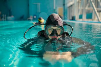 Male diver in scuba gear and mask poses in pool, course in diving school. Teaching people to swim underwater, indoor swimming. Man with aqualang