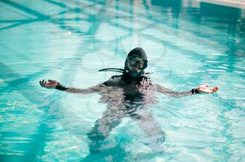 Male diver in scuba gear poses in pool, course in diving school. Teaching people to swim underwater, indoor swimming. Man with aqualang