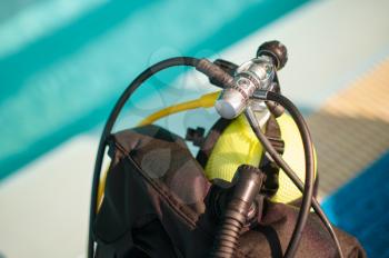 Oxygen tank at the poolside, scuba gear, aqualang, diving equipment. Teaching people to swim underwater, indoor swimming pool interior on background