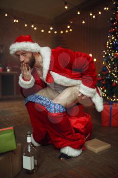Bad Santa claus pooping in gift box, nasty party, humor. Unhealthy lifestyle, bearded man in holiday costume, new year and alcoholism
