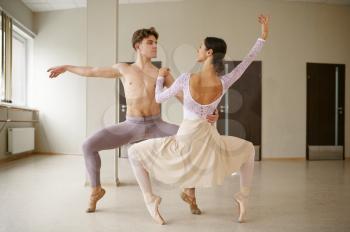 Couple of ballet dancers, performance in action. Ballerina with partner training in class, dance studio interior on background