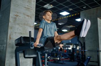 Youngster doing ABS exercise on machine in gym. Boy on fitness training in sport club, healthcare and healthy lifestyle, schoolboy on workout