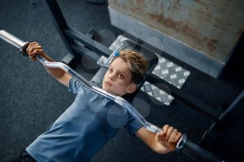 Boy on exercise machine, top view, training in gym. Youngster in sport club, healthcare and healthy lifestyle, schoolboy on workout, sportive youth