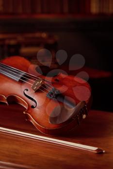 Violin in retro style and bow on wooden table, nobody. Classical string musical instrument, music art, old viola, dark background