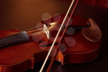 Violin in retro style and bow, closeup view, nobody. Classical string musical instrument, music art, old viola, dark background
