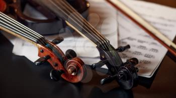 Retro violin and modern electric viola, closeup view, nobody. Two classical string musical instruments, music notebook on background