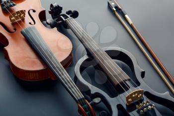 Bow, wooden retro violin and modern electric viola, closeup view, nobody. Two classical string musical instruments, black background