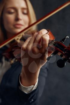 Female violonist with bow and violin, solo concert on stage. Woman with string musical instrument, music art, musician play on viola, dark background