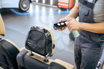 Worker applies agent on brush, car seat dry cleaning and detailing. Vehicle washing in garage, thoroughly care of automobile, chemical and vacuum clean service