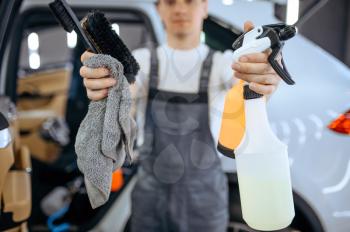 Worker shows tools for dry cleaning and detailing. Vehicle washing in garage, thoroughly care of automobile, chemical and vacuum clean service