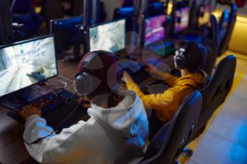 Two young gamers play in game club. Virtual entertainment, e-sport tournament, cybersport lifestyle. Male person leisures in internet cafe