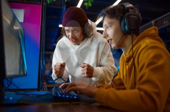 Two young gamers looks on monitor in gaming club. Virtual entertainment, e-sport tournament, cybersport lifestyle. Male person leisures in internet cafe