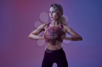 Young sportswoman with ball poses in studio, neon background. Fitness woman at the photo shoot, sport concept, active lifestyle motivation