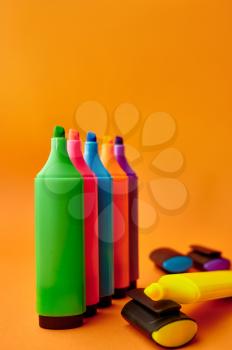 Standing colorful permanent markers closeup on orange background. Office stationery supplies, school or education accessories, writing and drawing tools