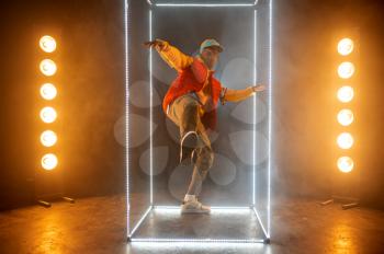 Stylish rapper on the stage with illuminated cube. Hip-hop performer, rap singer, break-dance performing, entertainment lifestyle