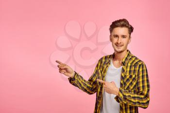 Happy man shows on wall, pink background, emotion. Face expression, male person looking on camera in studio, emotional concept, feelings