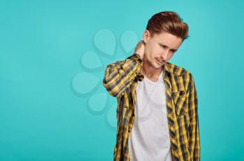 Young tired man portrait, blue background, emotion. Face expression, male person looking on camera in studio, emotional concept, positive feelings