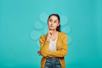 Mysterious cute woman, blue background, positive emotion. Face expression, female person looking on camera in studio, emotional concept, feelings