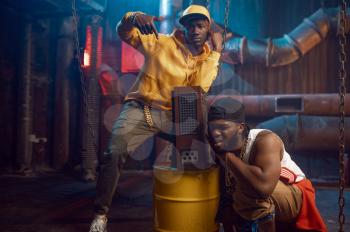 Two young rappers, break-dance performing in studio with cool underground decoration. Hip-hop performers, trendy rap singers, break-dancers