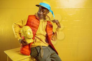 Young stylish rapper poses in studio with yellow tones. Hip-hop performer, rap singer, break-dance performing, entertainment lifestyle