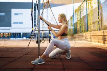 Smiling woman doing stretching exercise on sports ground outdoors. Slim female person in sportswear, outside fitness training, fit workout