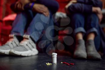 Drug addicts sitting on the floor in den, grunge place interoir on background, pill-addicted. Narcotic addiction problem, eternal depression of junky people