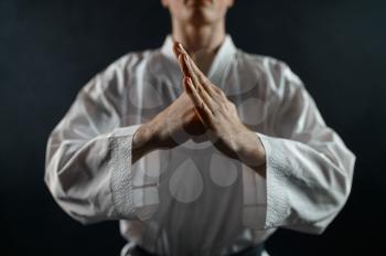 Male karate fighter in white kimono, welcome sign, dark background. Karateka on workout, martial arts, training before fighting competition