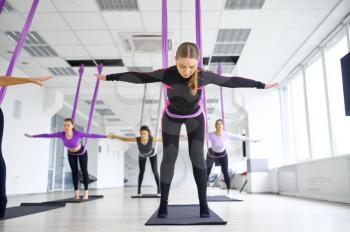 Aerial antigravity yoga, female group training with hammocks. Fitness, pilates and dance exercises mix. Women on yogi workout in sports studio