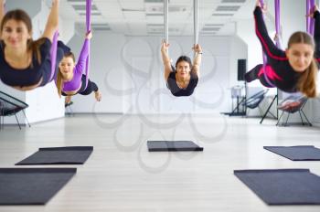 Fly anti-gravity yoga, female group training with hammocks. Fitness, pilates and dance exercises mix. Women on yoga workout in sport club