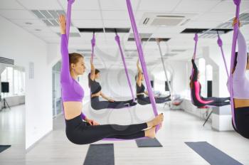 Fly anti-gravity yoga, female group training with hammocks. Fitness, pilates and dance exercises mix. Women on yoga workout in sports studio