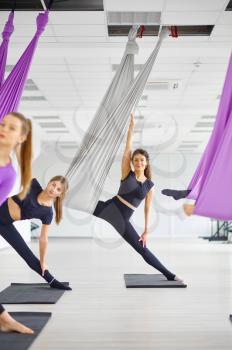 Fly yoga class, female group training, hanging on hammocks. Fitness, pilates and dance exercises mix. Women on yogi workout in sports studio