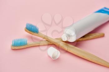 Oral care products, two toothbrush and toothpaste, pink background, nobody. Morning healthcare procedures concept, toothcare