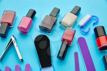 Nail care products, color polish in bottles on blue background, nobody. Healthcare procedures concept, fashion cosmetic, manicure and pedicure tools