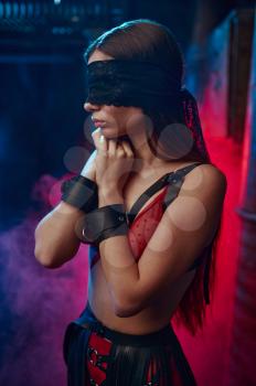 Sexy woman poses in bdsm blindfold and handcuffs, abandoned factory interior on background. Young girl in erotic underwear, sex fetish, sexual fantasy