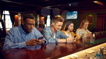 Friends using mobile phones at the counter in bar. Group of people relax in pub, night lifestyle, friendship, modern realities
