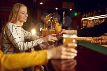 Two female friends drinks alcohol at the counter in bar. Group of people relax in pub, night lifestyle, friendship, event celebration