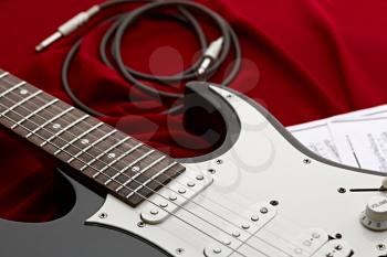 Black electric guitar, red background, nobody. String musical instrument, electro sound, electronic music