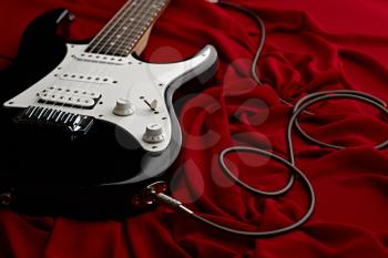 Black electric guitar, red background, nobody. String musical instrument, electro sound, electronic music, equipment for stage concert