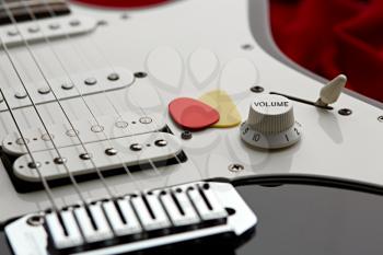 Electric guitar closeup, red background, nobody. String musical instrument, electro sound, electronic music, equipment for stage concert