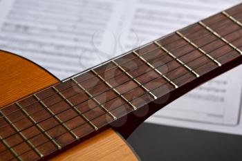 Acoustic guitar fretboard, music book on background, nobody. String musical instrument concept, live sound, equipment for musicians