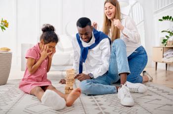 Happy family play game in living room. Mother, father and their little daughter poses at home together, good relationship. Mom, dad and female child, photo shoot in house