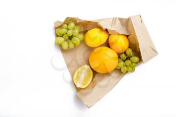 Fresh fruits in paper bag, top view, isolated on white background. Organic vegetarian food, grocery natural products, healthy lifestyle concept