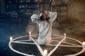 Scary demonic woman sitting in the magic circle, demons casting out. Exorcism, mystery paranormal ritual, dark religion, night horror, potions on shelf on background