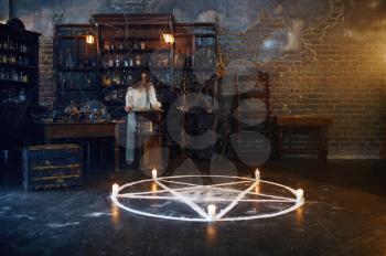 Young demonic woman reads book of spells, demons casting out. Exorcism, mystery paranormal ritual, dark religion, night horror, potions on shelf on background
