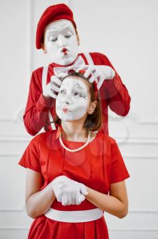 Two mime artists with face and hand makeup, red costumes. Pantomime theater, parody comedian, positive emotion, humour performance, funny face mimic and grimace