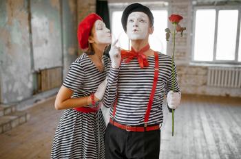Mime artists with makeup, kissing scene with rose, parody comedy. Pantomime theater, comedian, positive emotion, humour performance, funny face mimic and grimace