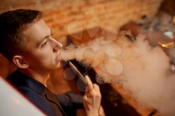 Young man smokes in hookah bar, hooka chill out. Shisha smoking, traditional bong culture, tobacco aroma for relaxation, rest with hooka