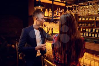 Young love couple smokes at the counter in hookah bar, hooka chill out. Shisha smoking, traditional bong culture, tobacco aroma for relaxation, rest with hooka